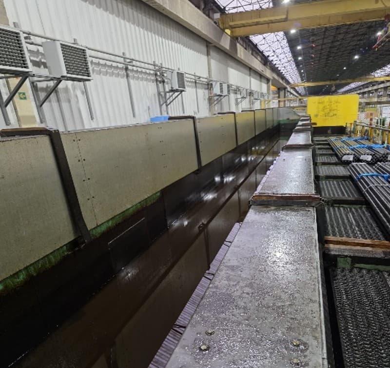 Oil bath treatment line — tubes are dipped for surface protection, then must drain completely before shipping